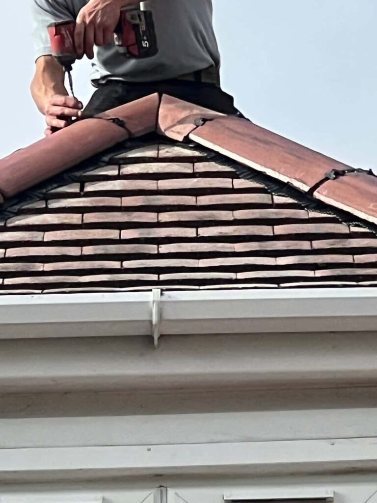 This is a photo of one of the operatives of Westerham Roofing Repairs installing new ridge tiles