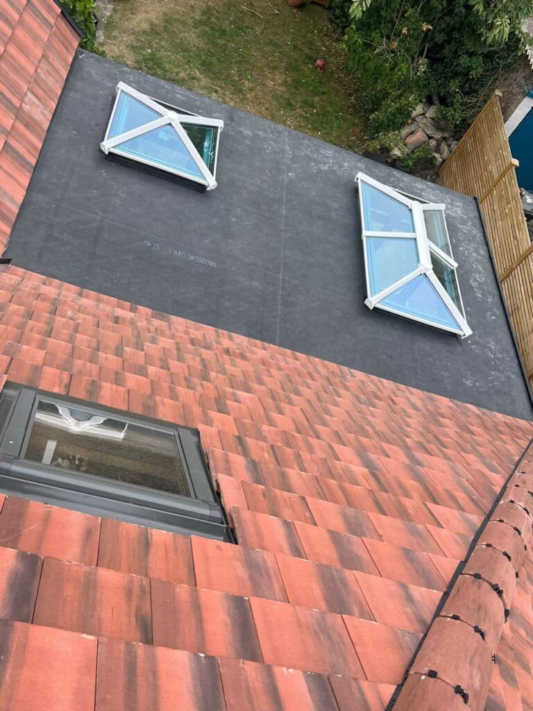 This is a photo taken from the roof ridge looking down a tiled pitched roof on to a flat roof. Works carried out by Westerham Roofing Repairs